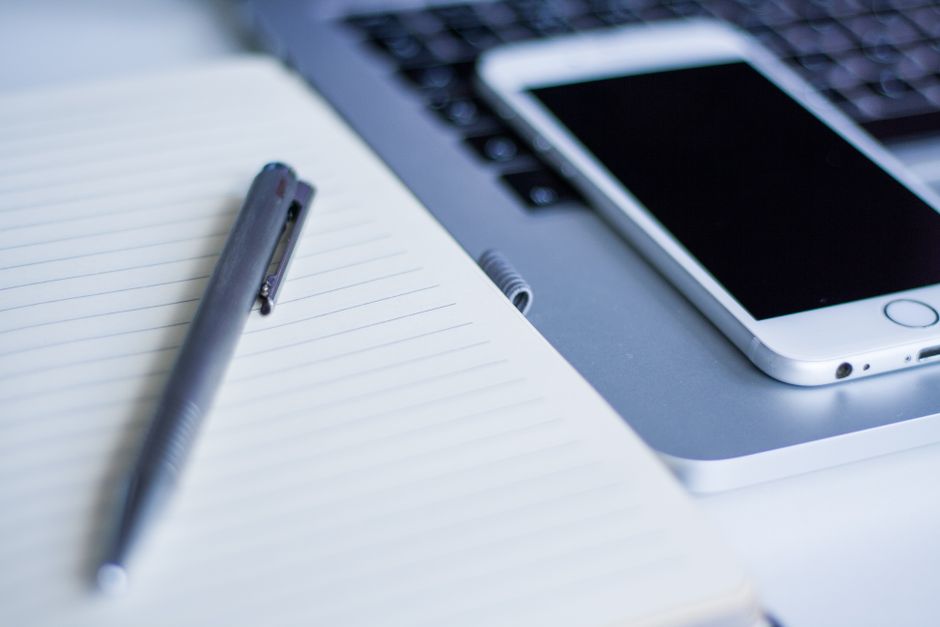 Close-up of a laptop, smartphone, and notebook pen on a desk. Ideal for tech, work, and productivity themes.