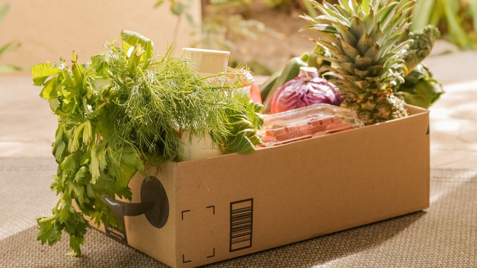 A cardboard box filled with fresh vegetables and fruits, perfect for delivery or online shopping.